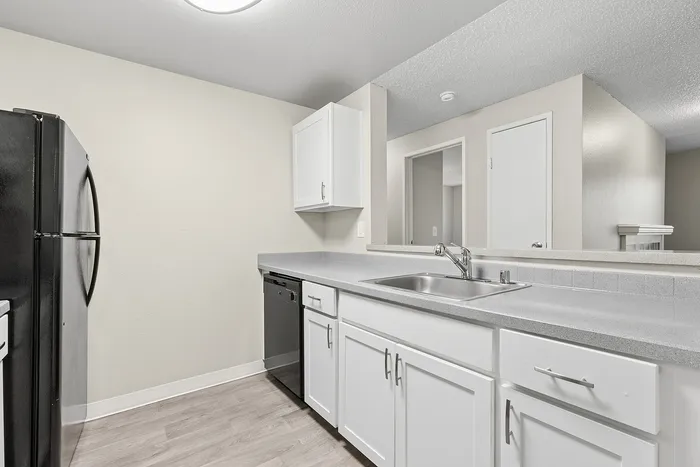 view 2 of kitchen in B1 renovated floorplan at Timber Flats white cabinets black appliances and grey countertops