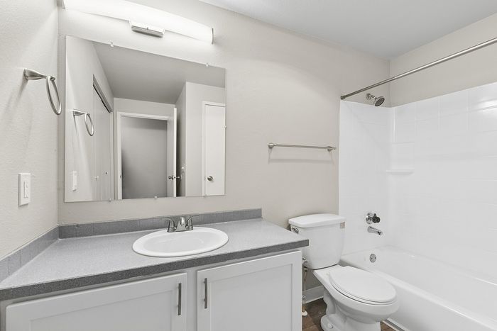 bathroom in B1 renovated floorplan at Timber Flats shower with tub and grey countertops white cabinets