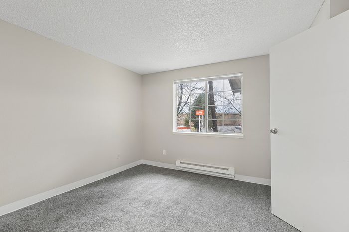 primary bedroom in B1 renovated floorplan at Timber Flats windows and carpeted