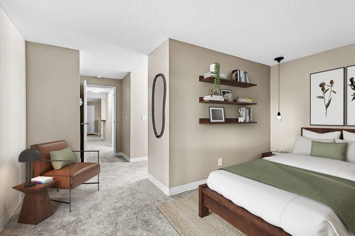 Timber flats bedroom with a bed, chair, shelves and art