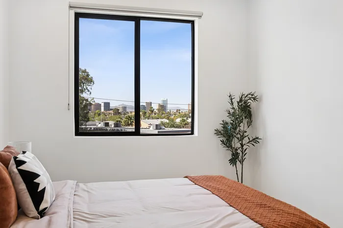 Midtown Phoenix, AZ, Apartments Near Phoenix Sky Harbor International Airport - Asa Midtown - Bright Bedroom With Large Window, City Skyline View, White Walls, And Warm Accent Bedding.
