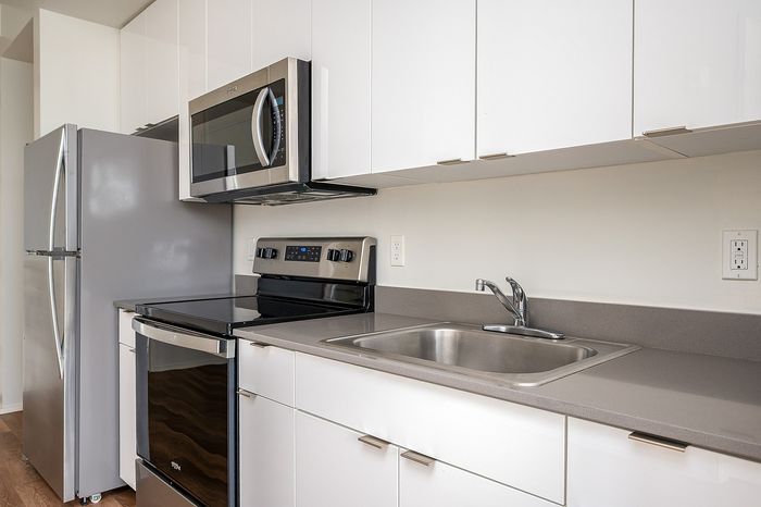 Closeup of kitchen at Lyra apartments with grey countertops and stainless steel appliances