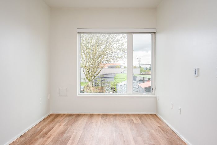 Living room at Lyra with a large window and hardwood floors