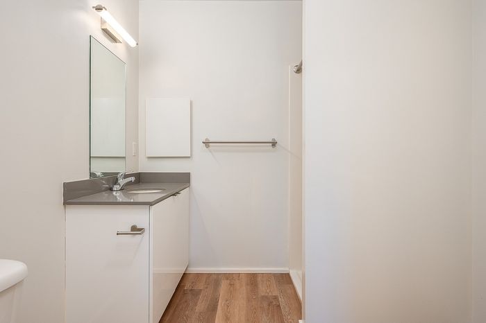 One Bedroom at Lyra Apartments - Bathroom with grey counter and hardwood floorps