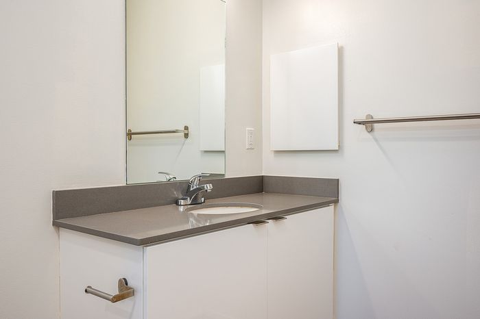 One Bedroom at Lyra Apartments - Bathroom with grey counter and mirror above the sinkfloors