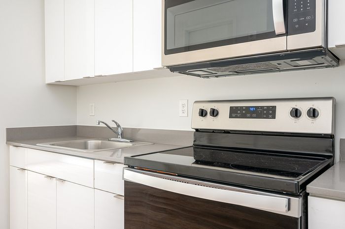 One-Bedroom at Lyra Apartments - closeup of kitchen with grey countertops and stainless steel appliances