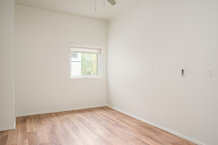 One-Bedroom at Lyra Apartments - bedroom with window, ceiling fan and hardwood floors