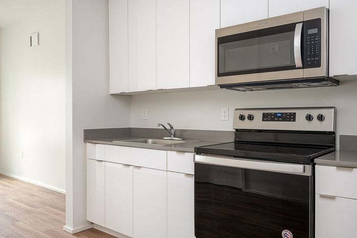 One-Bedroom at Lyra Apartments - closeup of kitchen with grey countertops and stainless steel appliances