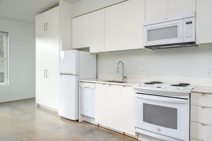Cassi Apartments - kitchen with white appliances and white countertops and cabinets