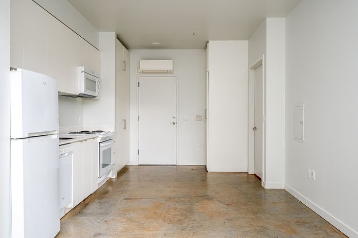 Cassi Apartments - kitchen with white appliances and white countertops and cabinets and view to the front door entryway