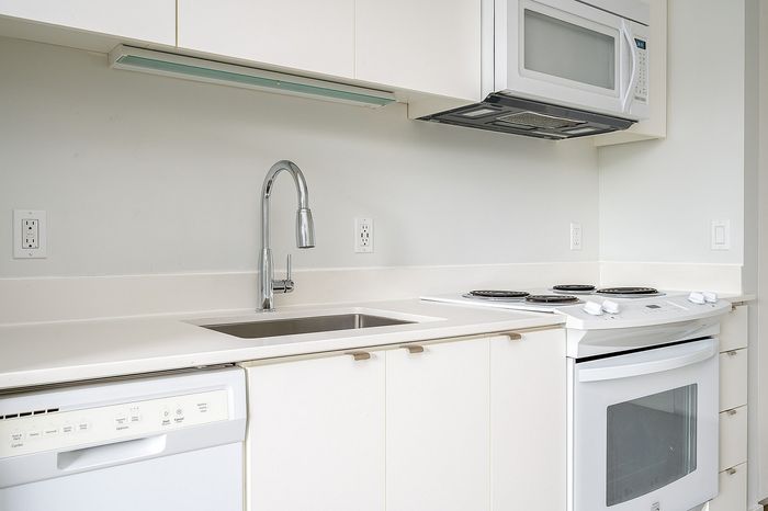 Cassi Apartments - kitchen with white appliances and white countertops and cabinets