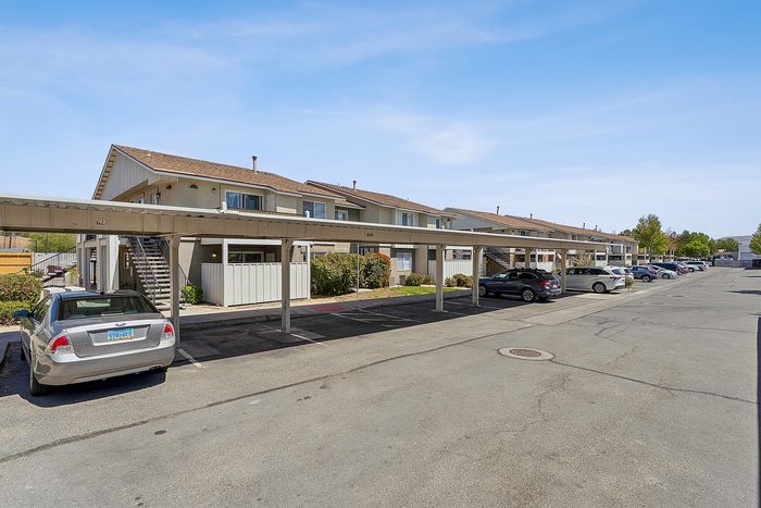 Parking lot with apartments and blue sky.
