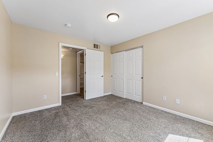 Bedroom with closet, carpet, and plastered walls.