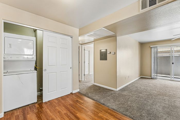 Living area with laundry, wooden floor, carpet, patio, and hallway.