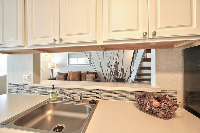 Stainless steel kitchen sink and white cabinets with a view of the stairs at CAMPBELL PARK.