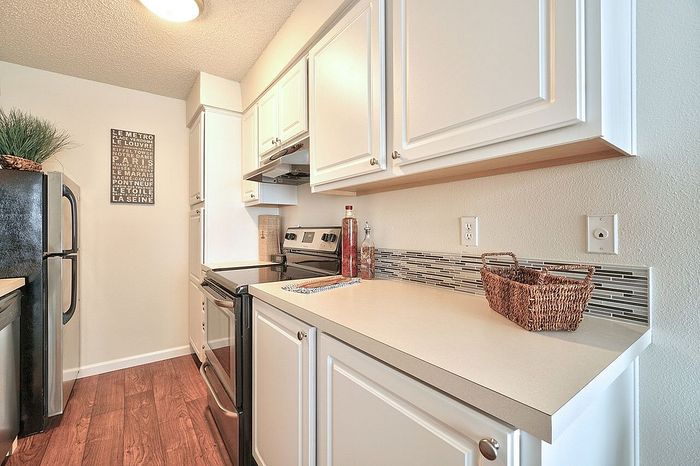 Modern kitchen workspace with a refrigerator and clean white counters at CAMPBELL PARK.