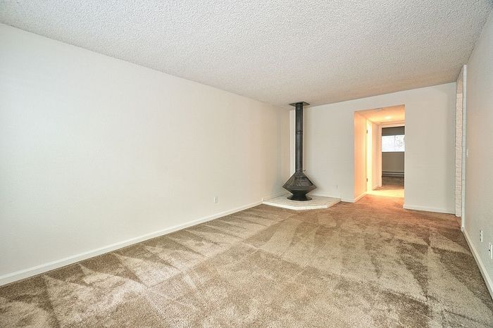 Empty apartment living room featuring a corner fireplace at CAMPBELL PARK.