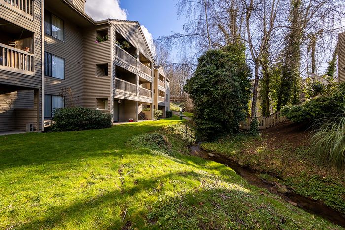 Multi-level apartment building exterior facing a grassy lawn at Creekwood Apartments.