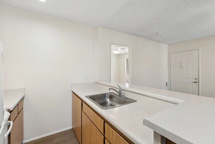 Kitchen at Orchard Mesa with wood cabinets, white appliances, white countertops and wood floors