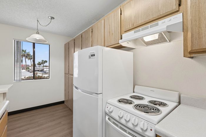 Kitchen at Orchard Mesa with wood cabinets, white appliances, white countertops and wood floors