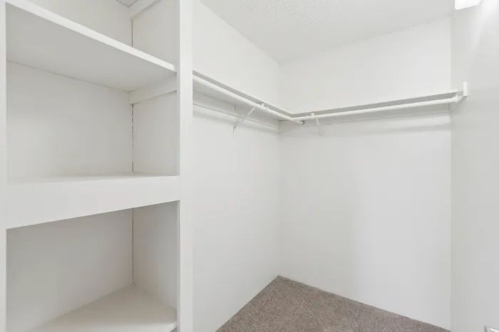 A walk-in closet with shelving and a rod to hang clothes