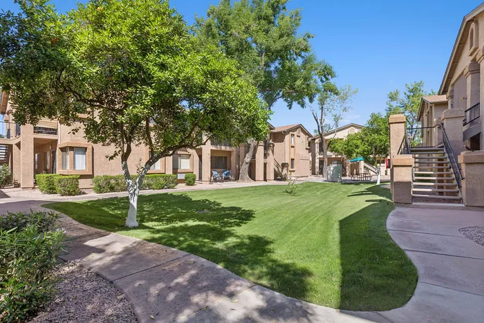 Grassy courtyard at Orchard Mesa with trees and walking path