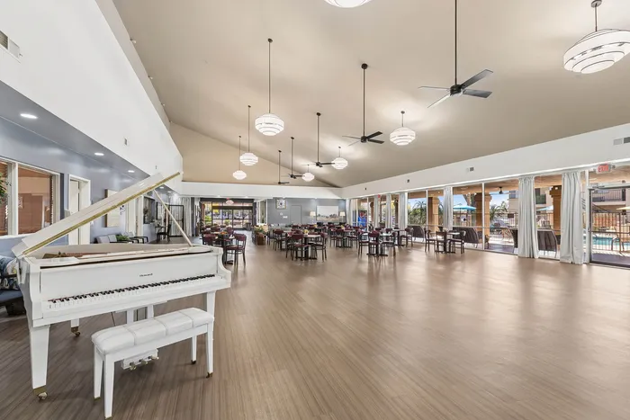 Community room with seating and a piano and a view out to the pool