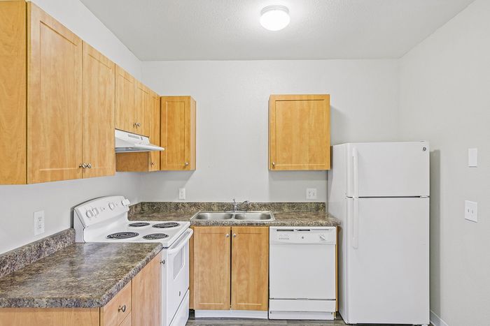 kitchen in the 1x1 floorplan at ventura villas with white appliances and woord cabinets