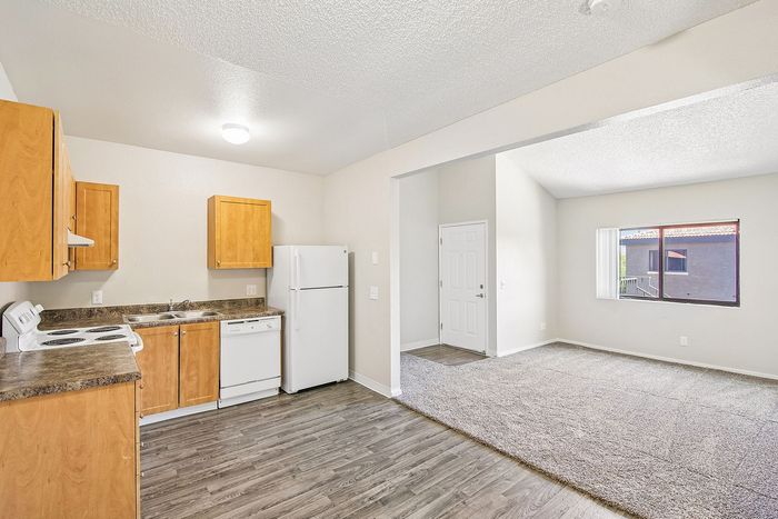 kitchen in the 1x1 floorplan at ventura villas with white appliances and woord cabinets with view into the living room