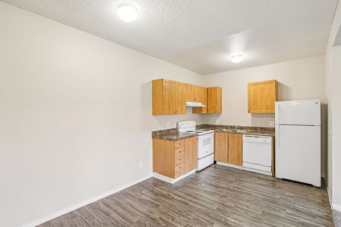 kitchen in the 1x1 floorplan at ventura villas with white appliances and woord cabinets with a dining area