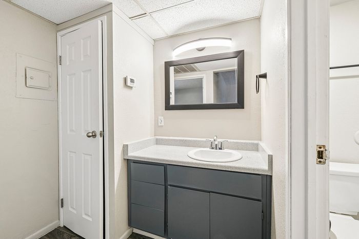 Bathroom at Deer Valley Village featuring a grey vanity, white sink, and framed mirror with modern light.