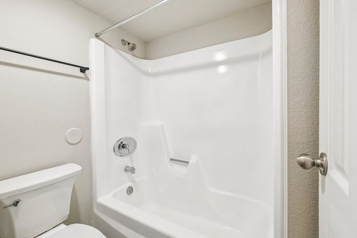 White shower and tub combo with chrome fixtures in a Deer Valley Village apartment home.