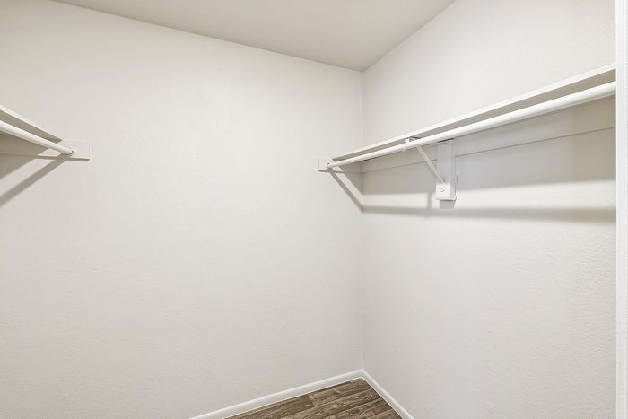 Spacious white closet with hanging rods and shelves in a Deer Valley Village apartment.