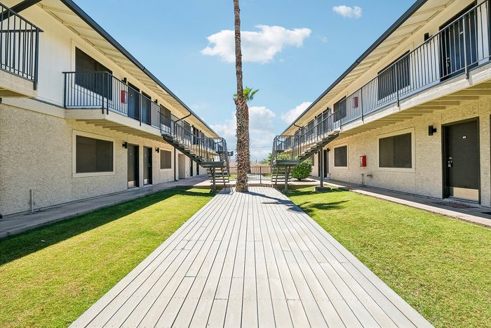 Deer Valley Village courtyard featuring a wooden walkway, green grass, and tall palm tree.
