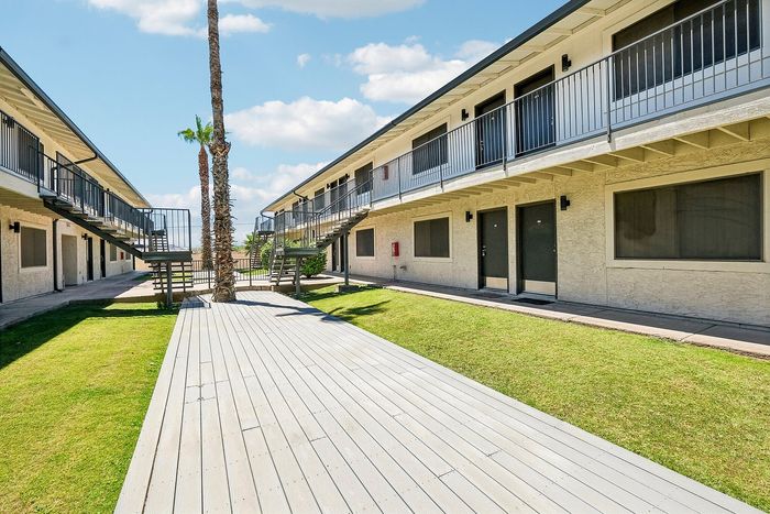 Landscaped courtyard at Deer Valley Village with a wooden walkway and lush green lawn.