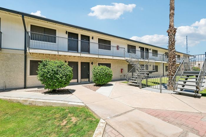 Exterior of Deer Valley Village buildings with concrete walkways, metal stairs, and manicured shrubs.