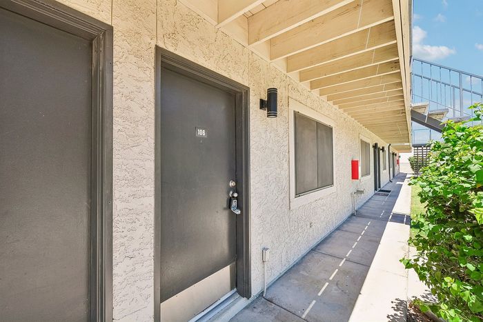 Entry door to a Deer Valley Village apartment home with exterior lighting and stucco walls.