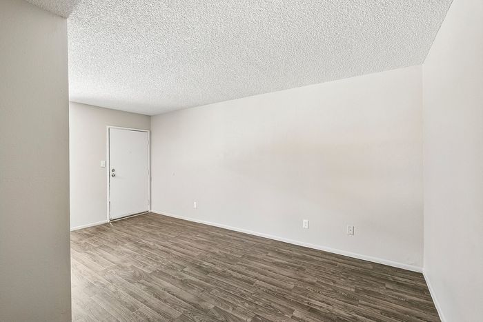 Open floor plan living room at Deer Valley Village with neutral walls and wood-style flooring.