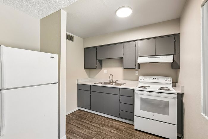 Kitchen at Deer Valley Village with grey cabinets, white electric range, and laminate countertops.
