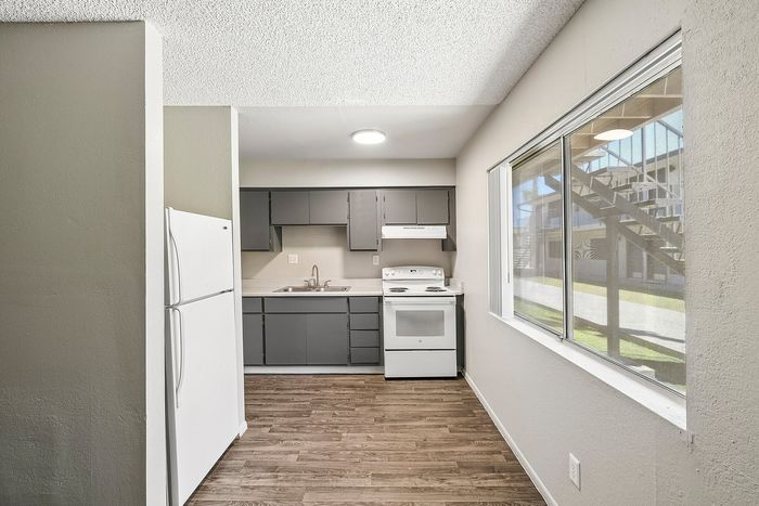 Open layout kitchen at Deer Valley Village with white appliances, grey cabinets, and wood-style flooring.