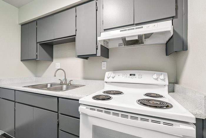 Detail of white electric range and grey upper cabinetry in a Deer Valley Village apartment kitchen.