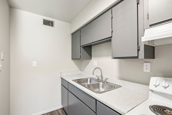 View of grey kitchen cabinets and stainless steel sink in a Deer Valley Village apartment home.