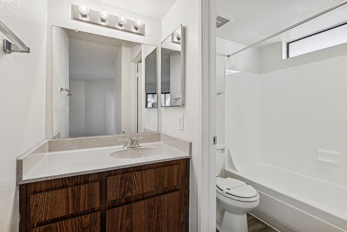 Bathroom with wood cabinets and a separate room with a toilet and shower/tub combo