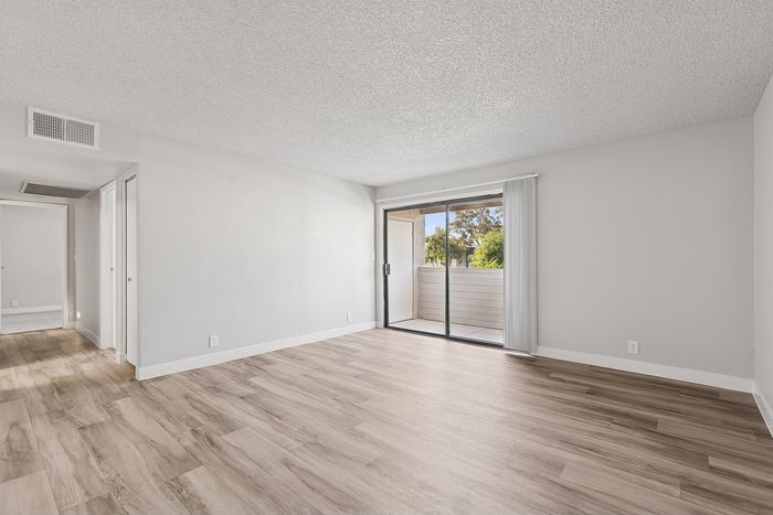 Living room in a unit at peoria grand with wood floors and a sliding glass door to the patio