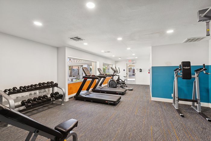 Gym at peoria grand with free weights, equipment and view out to the pool