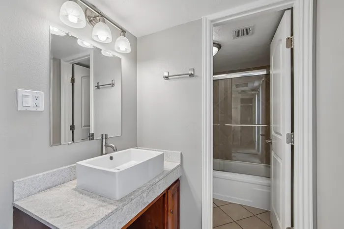 bathroom at solaris at the biltmore with wood cabinets and a white sink and a seperate room with toilet and shower