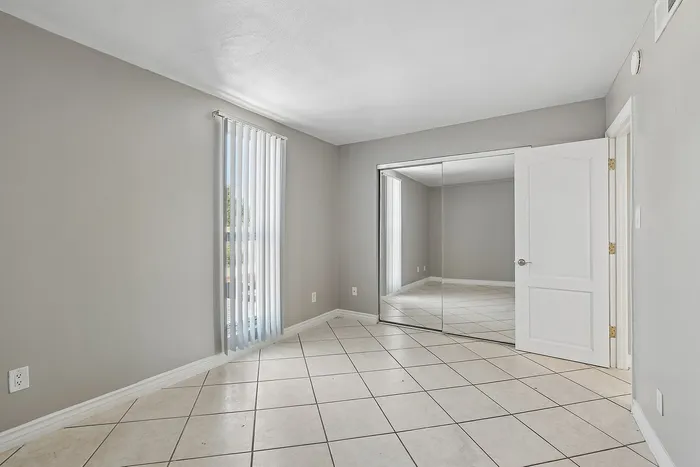bedroom at solaris at the biltmore with tile flooring and mirrored closet doors and a tall window