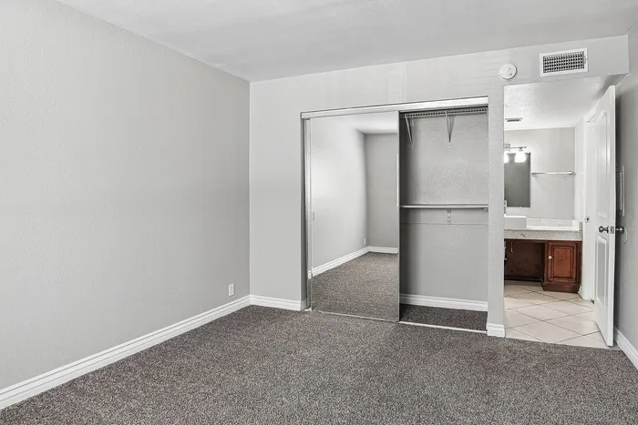 bedroom at Solaris at the biltmore with carpet and grey paint and a closet with mirrored doors and an attached bathroom