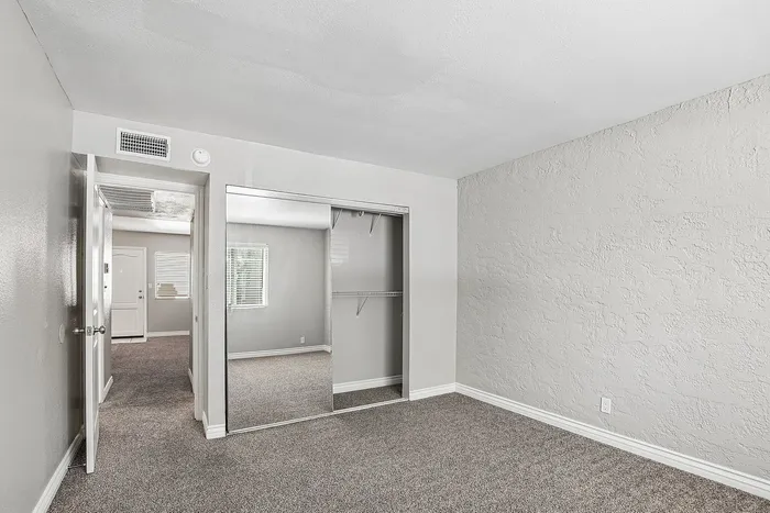 bedroom at Solaris at the biltmore with carpet and grey paint and a closet with mirrored doors