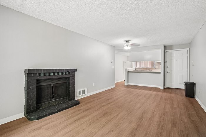 Living room at creekwood with a fireplace with black tile around it and hardwood floors